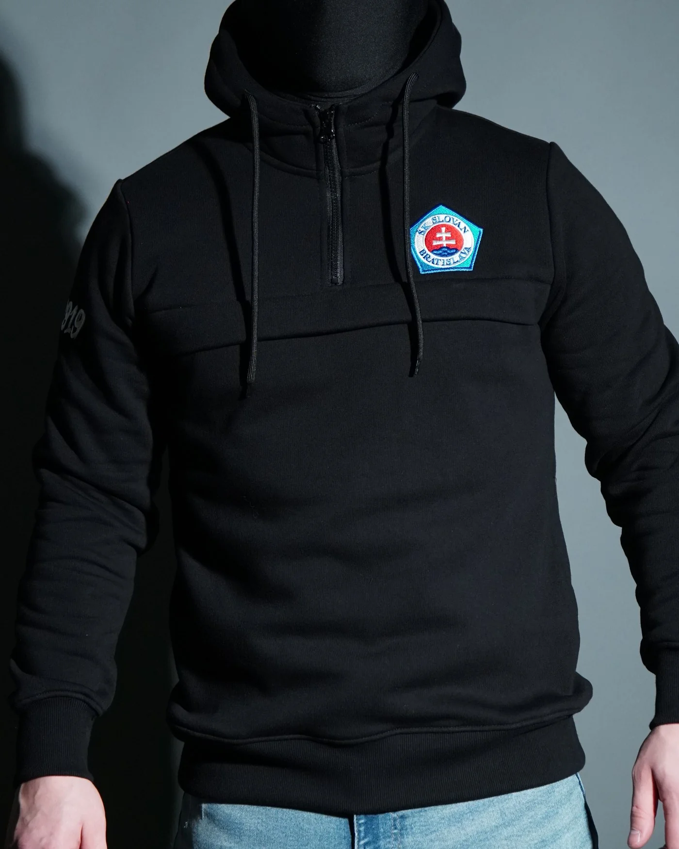 Czarna bluza z kapturem i poprzecznym panelem na przodzie, z naszywką klubową na piersi