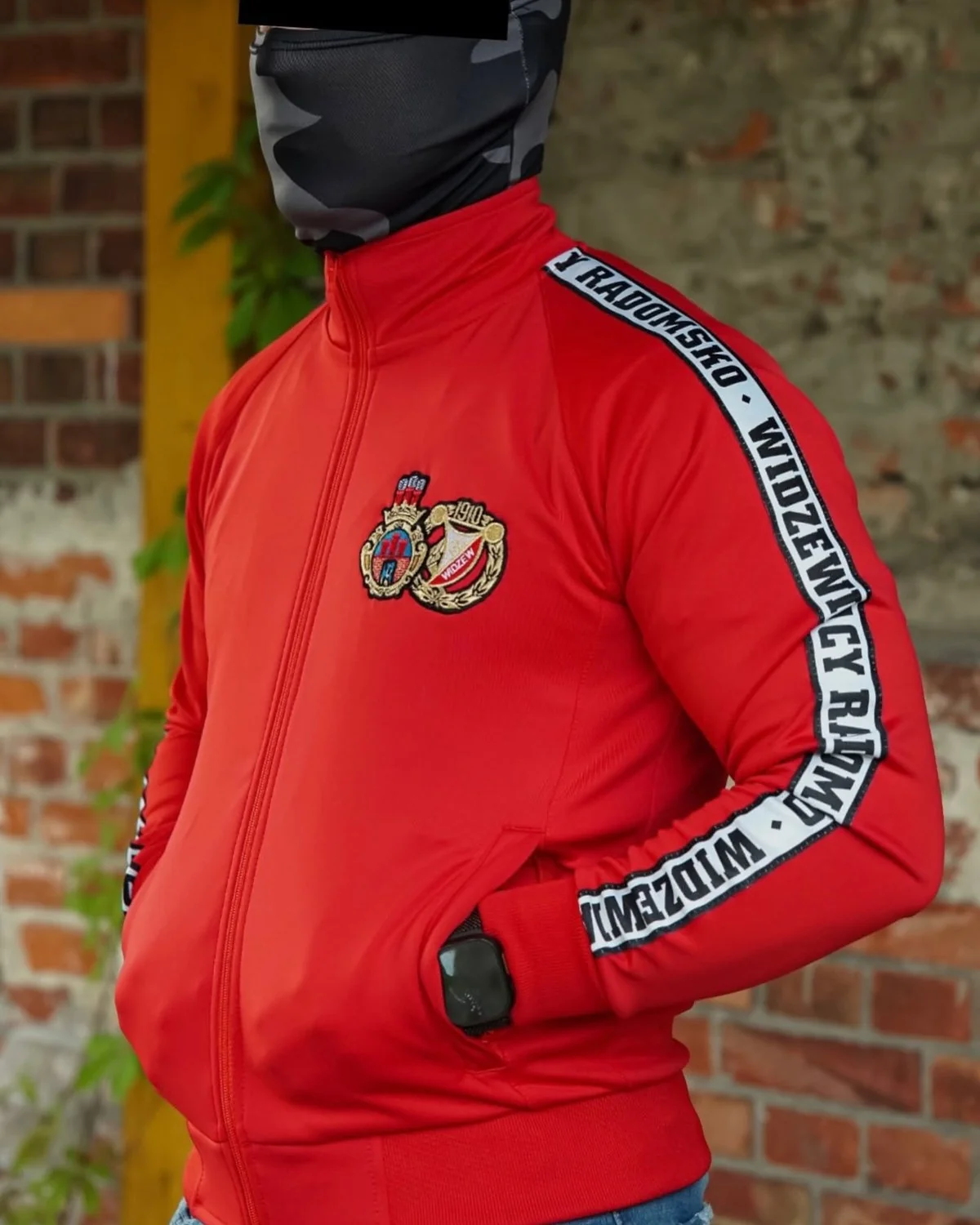 Czerwona bluza sportowa z ozdobną taśmą biegnącą wzdłuż rękawa