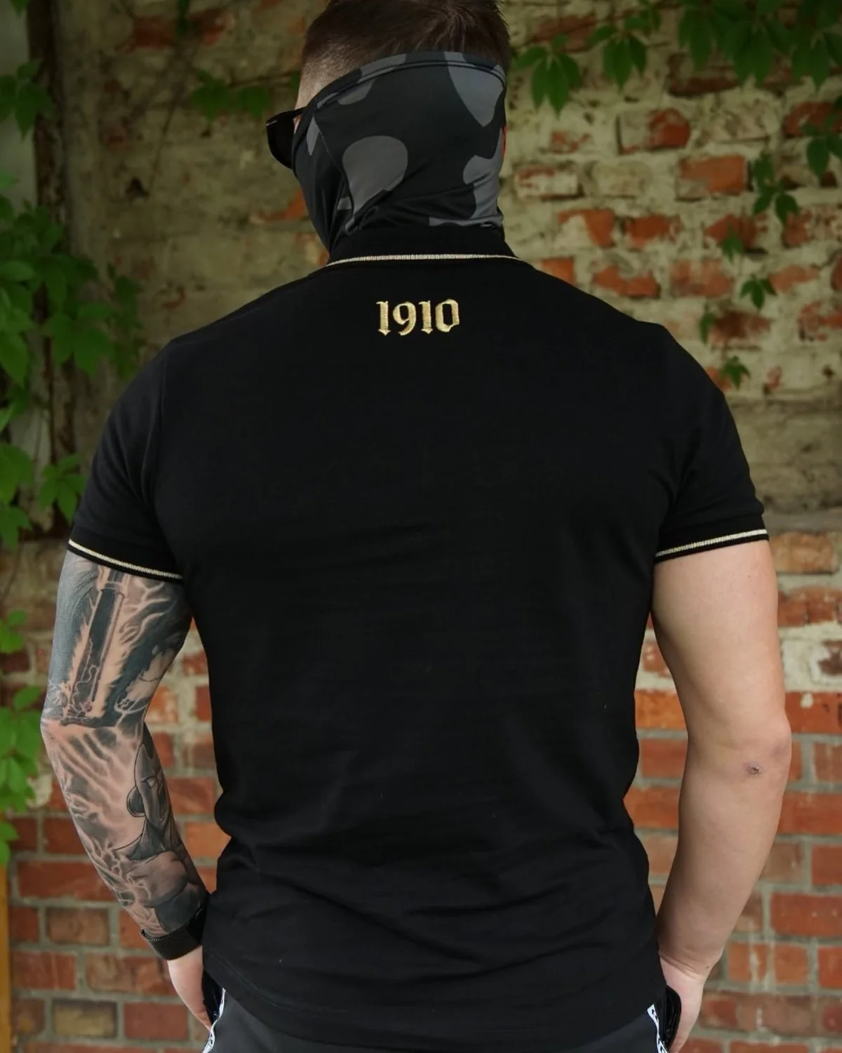 To samo czarne polo od tyłu, ze złotym napisem 1910 pod kołnierzykiem
