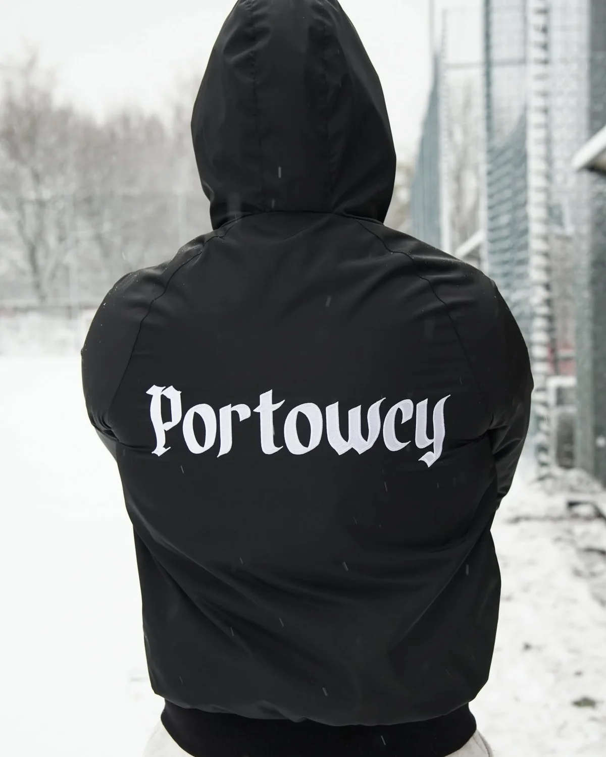 Czarna wiatrówka z kapturem z białym napisem Portowcy na plecach