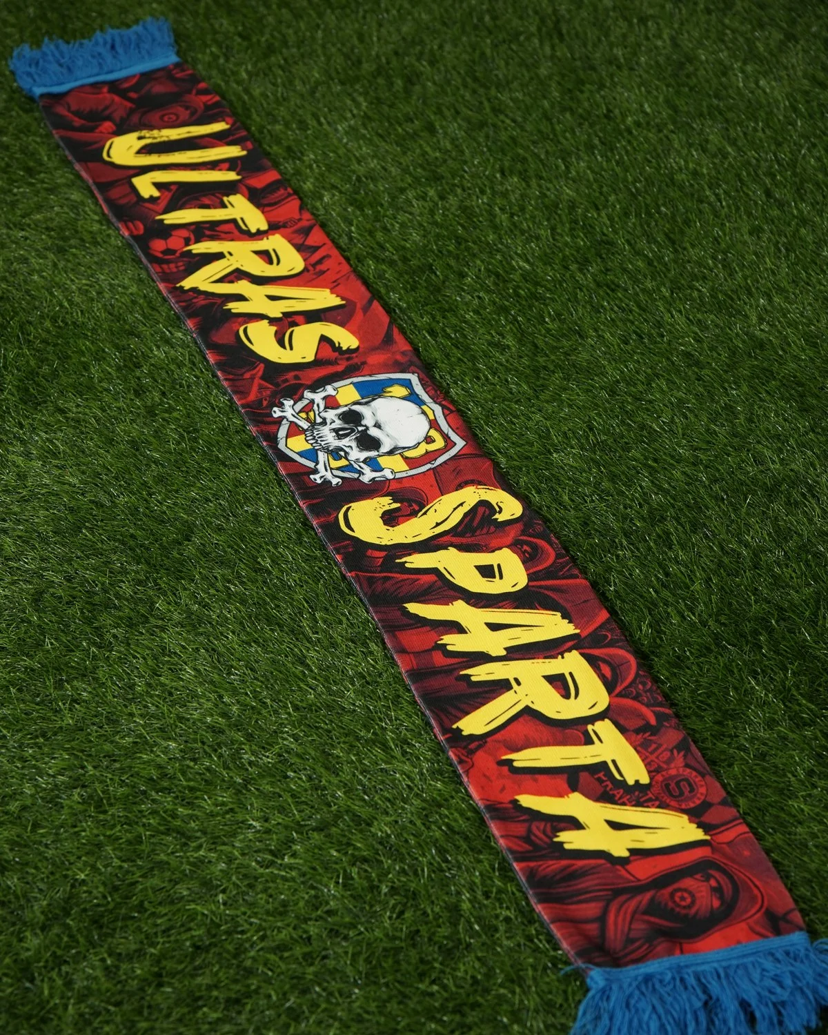 Czerwony szalik Ultras Sparta z żółtym napisem, czaszką w herbie i niebieskimi frędzlami