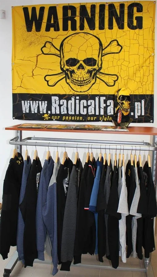 Kolekcja RadicalFans w łódzkim sklepie, nad wieszakami baner Warning