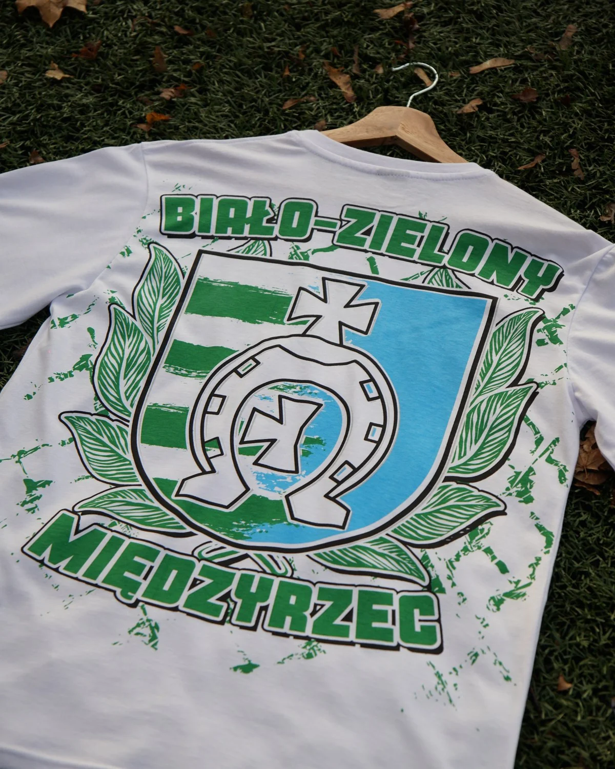 Biały T-shirt Orląt Radzyń Podlaski z zielono-niebieskim herbem i napisem Biało-Zielony Międzyrzec